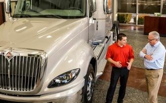 House of Trucks employee talking to customer next to truck